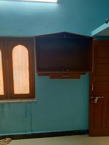 uma televisão de ecrã plano pendurada numa parede ao lado de 2 janelas em 1 BHK House with AC fully operational kitchen with wifi em Hyderabad
