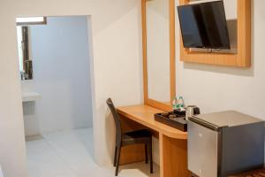 Votel Manyar Resort Banyuwangi في Ketapang: غرفة مع مكتب مع تلفزيون على الحائط