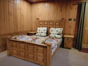 a bedroom with a wooden bed with two pillows at Kashmir Star Guest House & Family Resort in Nārān