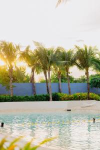 een zwembad met palmbomen op de achtergrond bij Bohemian Coast at Azure North in Lagundi