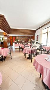 un restaurant avec des tables, des chaises et des tissus de table roses dans l'établissement Hotel Rey's, à Montegrotto Terme