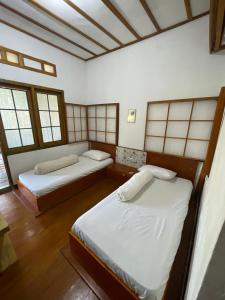 two beds in a room with two windows at Nua Indah Hotel & Resto Wakatobi in Wanci
