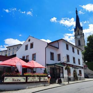 ein weißes Gebäude mit einem Uhrturm und einer Kirche in der Unterkunft Hotel die Traube in Admont