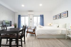 a white bedroom with a bed and a table and chairs at AL d' Cacilhas Studio in Almada