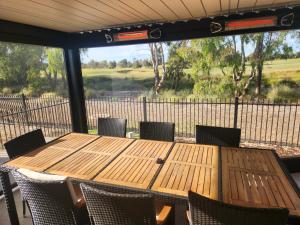 a wooden table and chairs with a view of a golf course at Bullseye in Yarrawonga