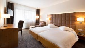 a hotel room with a large bed and a desk at Hotel Olympic - Montana Center in Crans-Montana