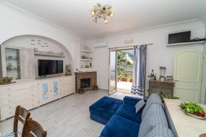 un soggiorno con divano blu e TV di Casa Melevyen in Positano a Positano