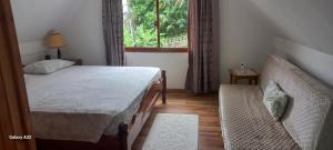 a bedroom with a bed and a window and a couch at Loversnest Self Catering in Anse aux Pins