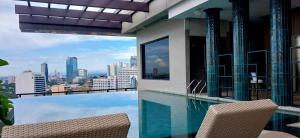 a swimming pool with two chairs and a view of the city at Harolds Evotel Quezon City in Manila