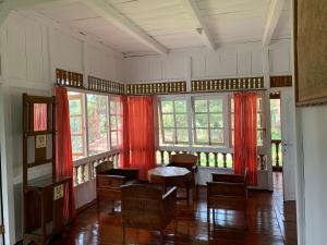 a room with red curtains and a table and chairs at Villa Kayu Puncak by Henny Ariastoeti in Campaka