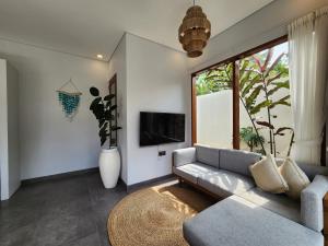 un salon avec un canapé et une grande fenêtre dans l'établissement villa 2 kamar di canggu kawaii villa, à Denpasar