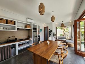 Il dispose d'une cuisine et d'un salon avec une table et des chaises en bois. dans l'établissement villa 2 kamar di canggu kawaii villa, à Denpasar