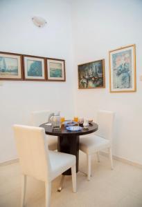 a dining room table with white chairs and paintings on the wall at La Grande Suite de Tozeur in Tozeur