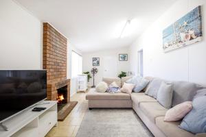 a living room with a couch and a fireplace at Crystal Bay - Pet Friendly - 3 Mins Walk to Beach in Callala Beach