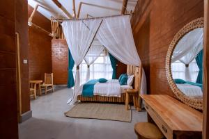 a bedroom with a bed with a canopy and mirrors at Mara Safari Lodge Kidepo 