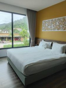 a bedroom with a large bed with a large window at TOBEDzZ HOTEL in Ranong