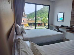 1 dormitorio con 2 camas y ventana grande en TOBEDzZ HOTEL en Ranong