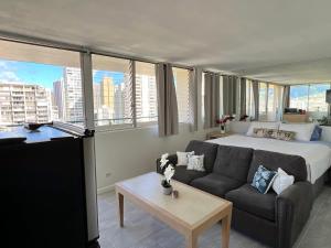 a bedroom with a bed and a couch in a room with windows at Penthouse in Waikiki with ocean & mountain views in Honolulu