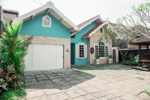 een blauw huis met een witte garage bij Tamu Ibu by Ubu Villa - 5 Bedrooms Villa in Yogyakarta in Beran-kidul