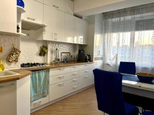 een keuken met witte kasten en een blauwe stoel bij Airport-apartament 24&24 Chişinău!!! in Chişinău