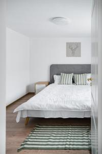 Acasă la Doftana في Teşila: غرفة نوم بسرير مع شراشف بيضاء وسجادة