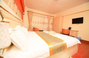 sypialnia z dużym białym łóżkiem i telewizorem w obiekcie Gold Suite Hotel w mieście Nakuru