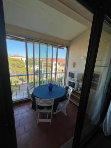 ein Esszimmer mit einem Tisch und Stühlen sowie einem Balkon in der Unterkunft Studio dans résidence, piscine lagon, tennis et aire de jeux in Fréjus