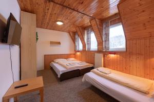 Habitación con 2 camas, mesa y TV. en Chata Miroslav, en Lipová-lázně