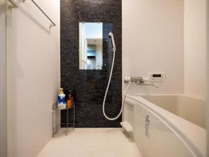 ein Bad mit einer Dusche, einem Waschbecken und einem Spiegel in der Unterkunft Sumiyoshi Marie - Vacation STAY 12160 in Osaka