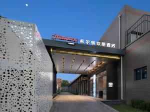 un bâtiment avec un panneau sur son côté dans l'établissement Hampton by Hilton Beijing South Railway Station, à Pékin
