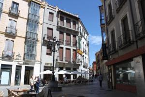 una via cittadina con tavoli, ombrelloni e edifici di Hotel Rey Niño ad Ávila