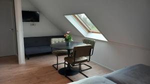 a room with a table and chairs and a window at B&B t'bûtefjild in De Valom