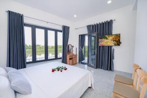 1 dormitorio con cama blanca y ventana grande en Moon River House en Hoi An