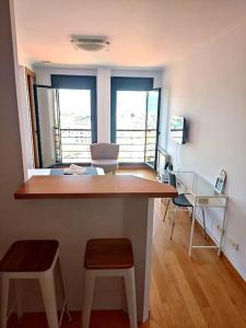 een kamer met een bureau met 2 krukken en 2 ramen bij Loft By Vialia in Vigo