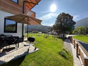 a patio with a grill and an umbrella at Mei-so-nett Appartement Hutegger in Schladming