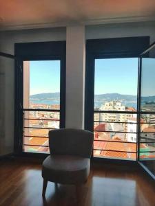 een stoel in een kamer met 2 grote ramen bij Loft By Vialia in Vigo
