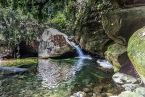 une cascade dans une piscine d'eau à côté de quelques rochers dans l'établissement Vale da Paz, à Guapimirim