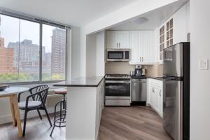 a kitchen with stainless steel appliances and a table with chairs at Kips Bay 1br w gym doorman nr hospitals NYC-1271 in New York