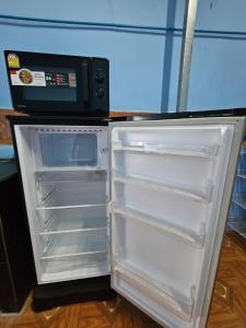 un réfrigérateur vide avec sa porte ouverte à côté d'un four micro-ondes dans l'établissement Paksong Brand New- Two-story house, à Muang Pakxong