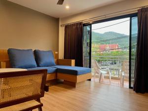 un soggiorno con divano blu e balcone di Room Actually Service Apartment a Karon Beach