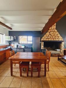 eine Küche mit einem Holztisch und einem Kamin in der Unterkunft Verregaande Cottage with hot tub in Agulhas