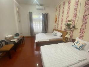 a room with four beds and a window with curtains at Villa sân vườn Misa in Phan Thiet