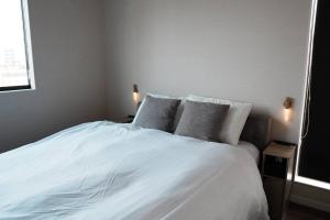 a bedroom with a white bed with two pillows at 【 STAY Chill ~omura~】長崎空港から車で10分！ in Omura