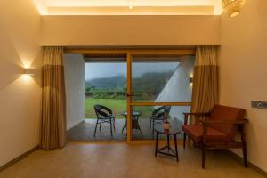 een woonkamer met een glazen schuifdeur met een tafel en stoelen bij Touchwood Bliss Igatpuri in Nashik