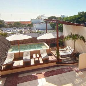 a pool with chairs and umbrellas on a patio at 3B Wellness Hostel in Playa del Carmen