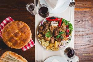 einen Tisch mit einem Teller Essen und einem Kuchen in der Unterkunft Garni hotel Niksic in Nikšić