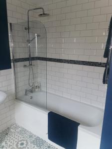 uma banheira branca com um chuveiro e uma toalha azul em Shepherd's Rest Apartments Central Location With Parking em Tewkesbury