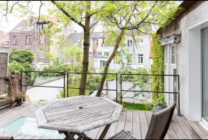 eine Holzterrasse mit einem Tisch und Stühlen auf dem Balkon in der Unterkunft Bohemian city loft in Gent