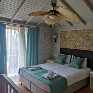 a bedroom with a bed with a ceiling fan at Hotel 212 Olympos in Olympos