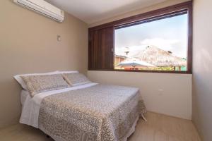 a bedroom with a bed and a large window at Casa de praia completa in Paulista
